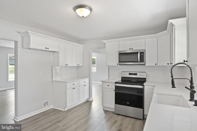 kitchen featuring a sink, stainless steel appliances, light countertops, and white cabinets