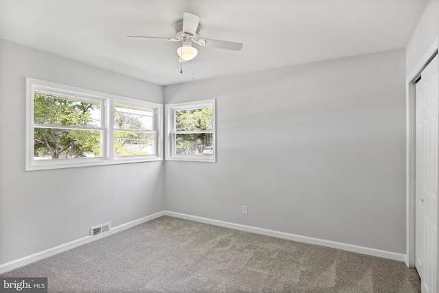 spare room featuring plenty of natural light, carpet, visible vents, and baseboards