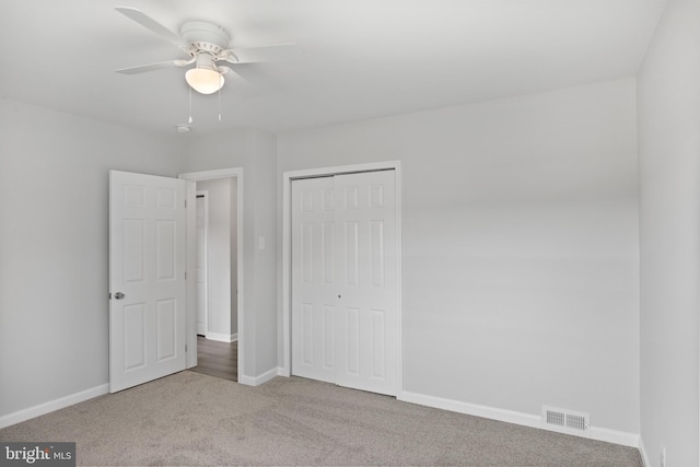 unfurnished bedroom featuring a closet, visible vents, a ceiling fan, light carpet, and baseboards