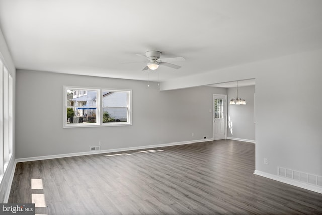 empty room with dark wood finished floors, visible vents, and baseboards