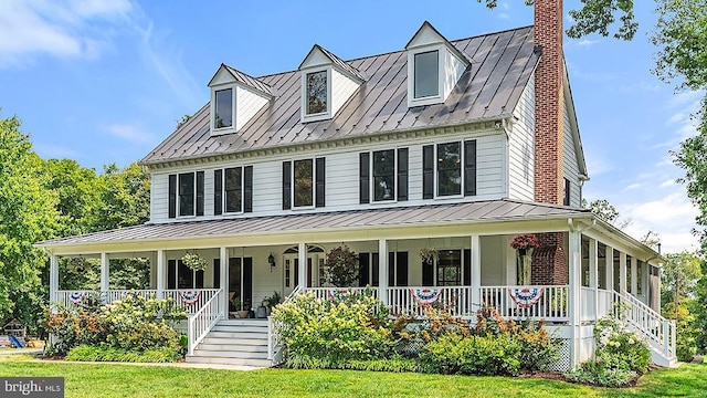 view of front facade featuring a standing seam roof, covered porch, metal roof, and a chimney