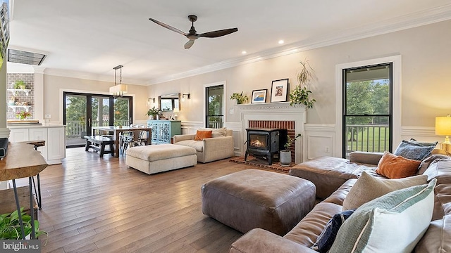 living room featuring a healthy amount of sunlight, hardwood / wood-style flooring, crown molding, and a wainscoted wall