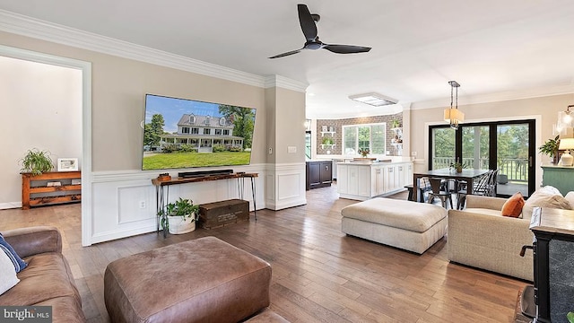 living area featuring a wealth of natural light, crown molding, and hardwood / wood-style flooring