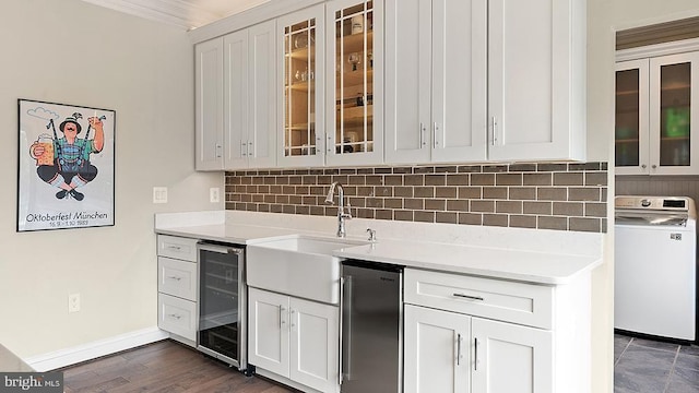 kitchen with beverage cooler, a sink, light countertops, decorative backsplash, and washer / dryer