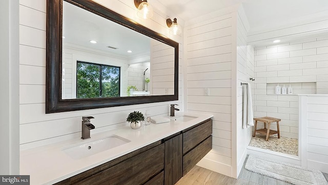 full bathroom featuring wood finished floors, double vanity, a sink, and walk in shower