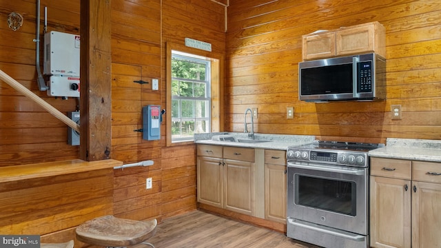 kitchen with stainless steel appliances, a sink, and wooden walls