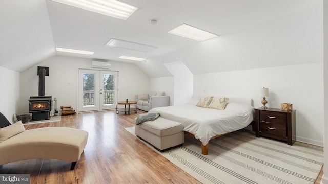 bedroom with a wall unit AC, light wood-style floors, access to outside, and lofted ceiling