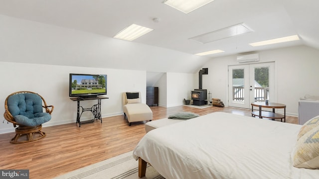 bedroom with lofted ceiling, a wall unit AC, light wood-style flooring, access to exterior, and french doors