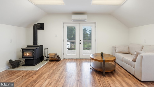 living room featuring wood finished floors, vaulted ceiling, french doors, a wall mounted AC, and a wood stove