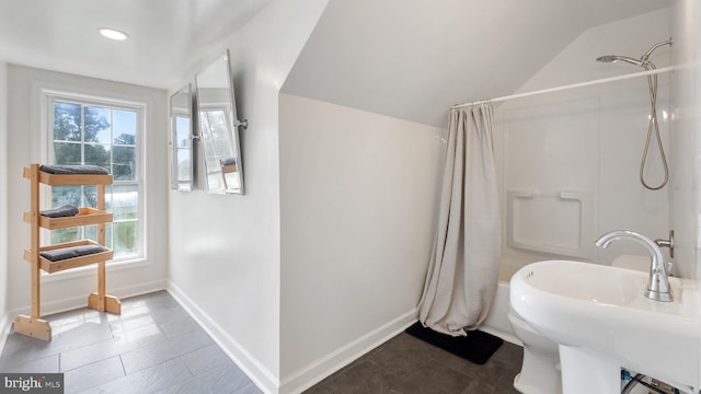 full bath featuring lofted ceiling, baseboards, and a sink