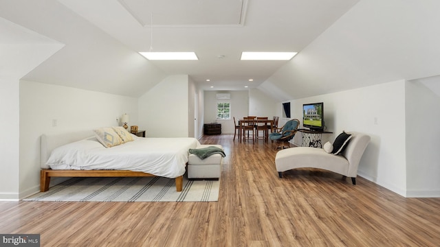 bedroom featuring vaulted ceiling, wood finished floors, attic access, and baseboards