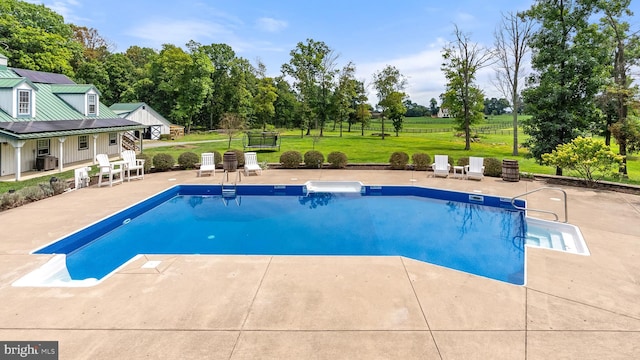 outdoor pool featuring a patio area, fence, and a yard