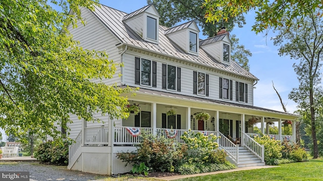 view of front of house featuring a standing seam roof, covered porch, metal roof, and a chimney