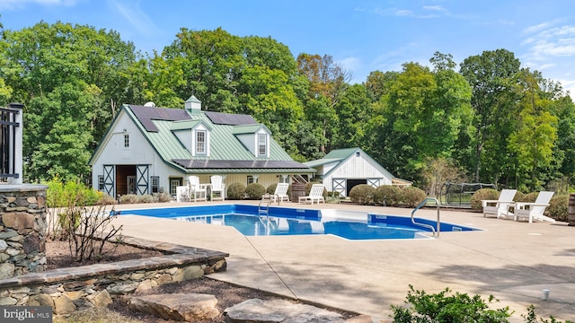 pool with a trampoline, a patio, an outdoor structure, and fence