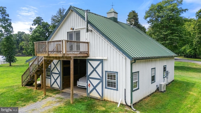 back of house with an outbuilding, metal roof, ac unit, a yard, and board and batten siding