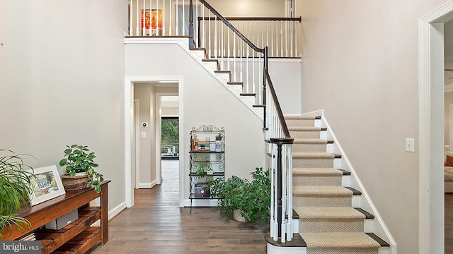 entrance foyer with stairs, a high ceiling, wood finished floors, and baseboards