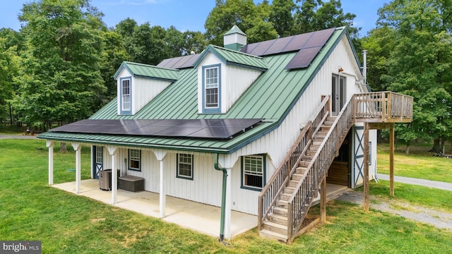 exterior space with a standing seam roof, a lawn, solar panels, and a patio