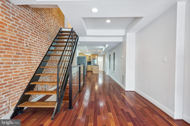 interior space featuring baseboards, brick wall, stairway, dark wood-type flooring, and recessed lighting