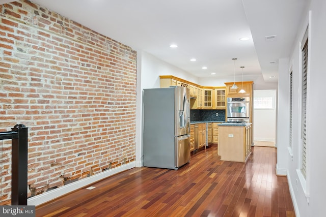 kitchen featuring hanging light fixtures, appliances with stainless steel finishes, glass insert cabinets, a kitchen island, and brick wall