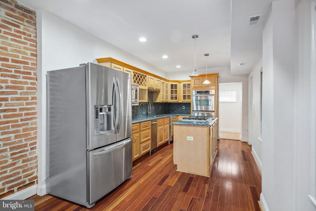 kitchen featuring a center island, stainless steel appliances, visible vents, hanging light fixtures, and glass insert cabinets