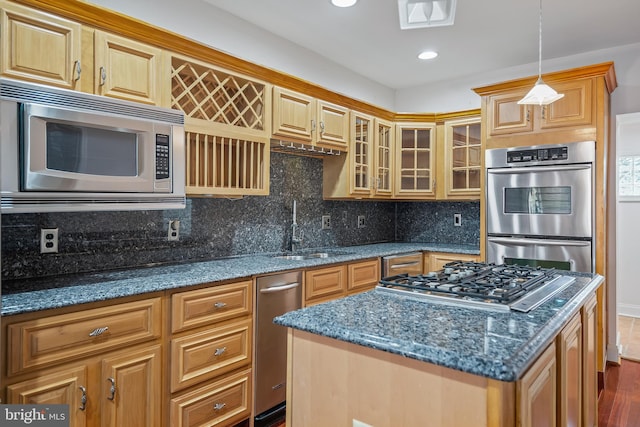 kitchen featuring dark stone counters, glass insert cabinets, appliances with stainless steel finishes, a sink, and backsplash