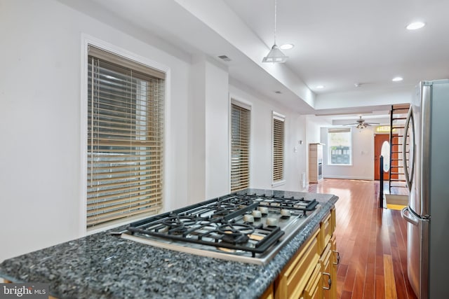 kitchen featuring appliances with stainless steel finishes, dark wood finished floors, hanging light fixtures, and dark stone countertops