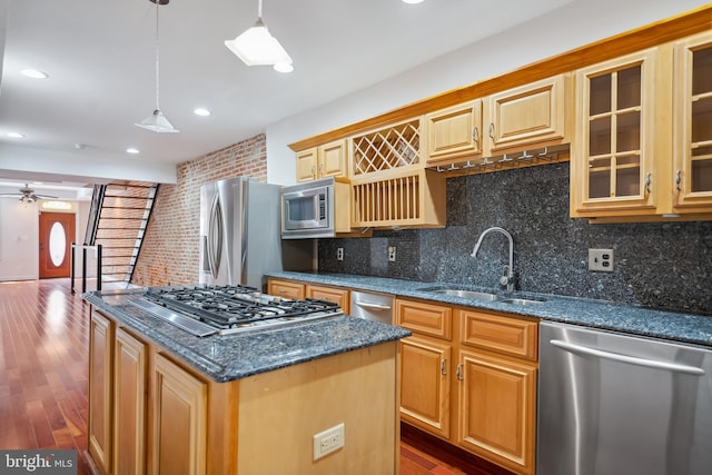 kitchen with a kitchen island, glass insert cabinets, stainless steel appliances, pendant lighting, and a sink