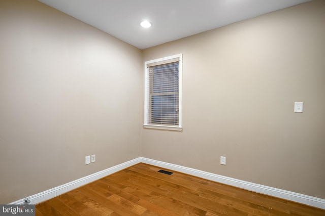 unfurnished room featuring baseboards, visible vents, and wood finished floors