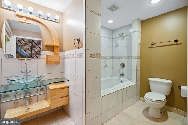 full bath with visible vents, toilet, a sink, tile patterned flooring, and tile walls