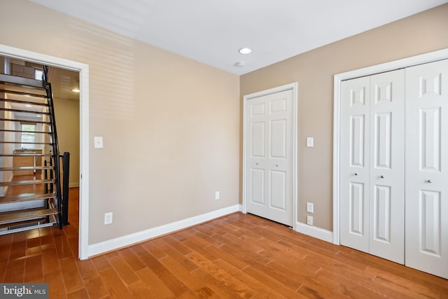 unfurnished bedroom featuring recessed lighting, a closet, baseboards, and wood finished floors