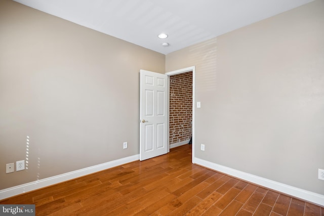 spare room featuring baseboards, wood finished floors, and recessed lighting