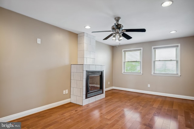 unfurnished living room featuring recessed lighting, a tiled fireplace, wood finished floors, and baseboards