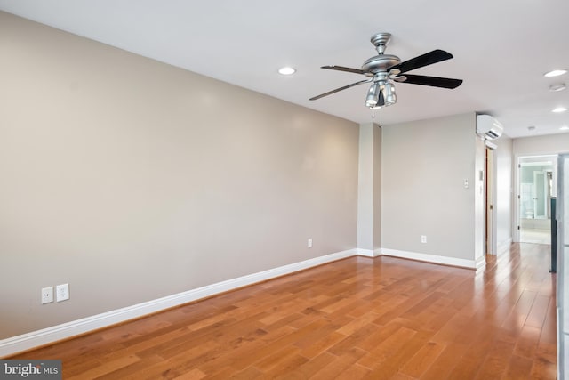 unfurnished room with recessed lighting, a wall unit AC, baseboards, and wood finished floors