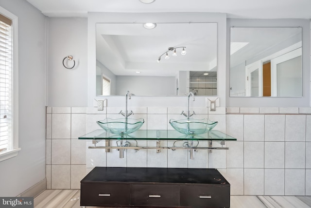 bathroom with double vanity, tile walls, and a sink