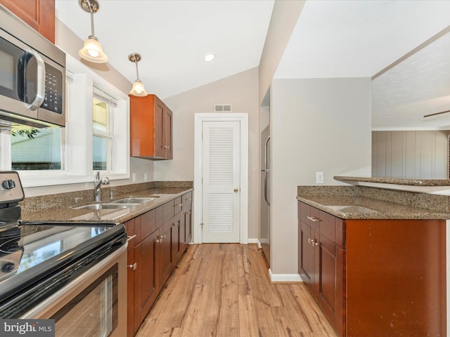 kitchen with a sink, light wood-style floors, stone counters, and stainless steel appliances