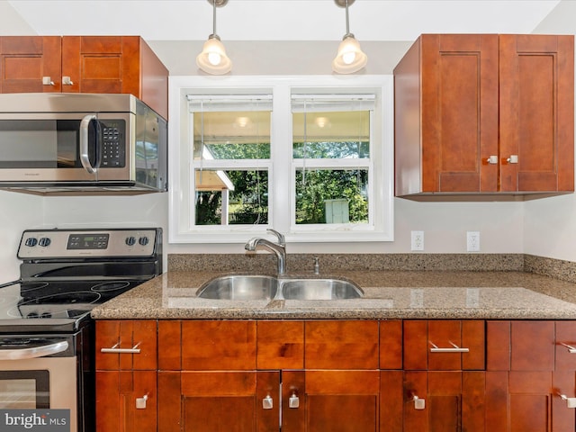 kitchen featuring pendant lighting, stone countertops, stainless steel appliances, and a sink