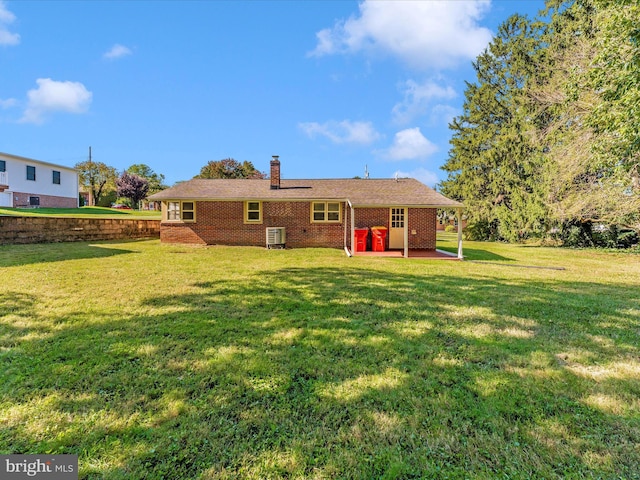 rear view of property featuring brick siding, a patio area, a lawn, and a chimney