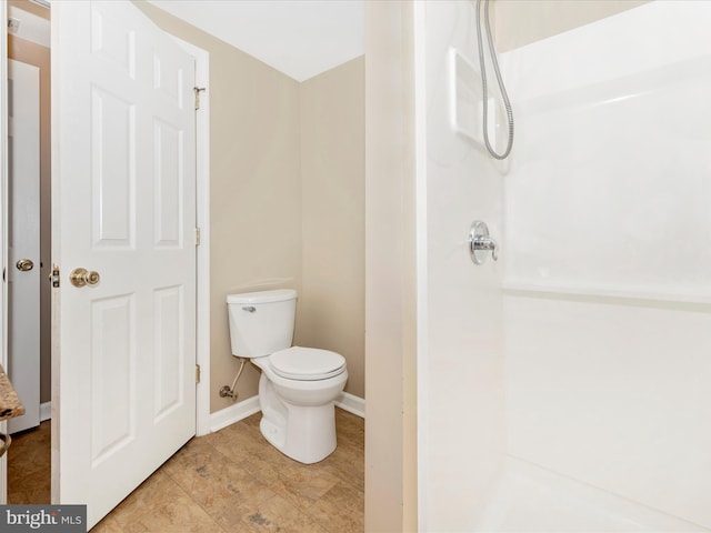 bathroom with baseboards, toilet, and walk in shower