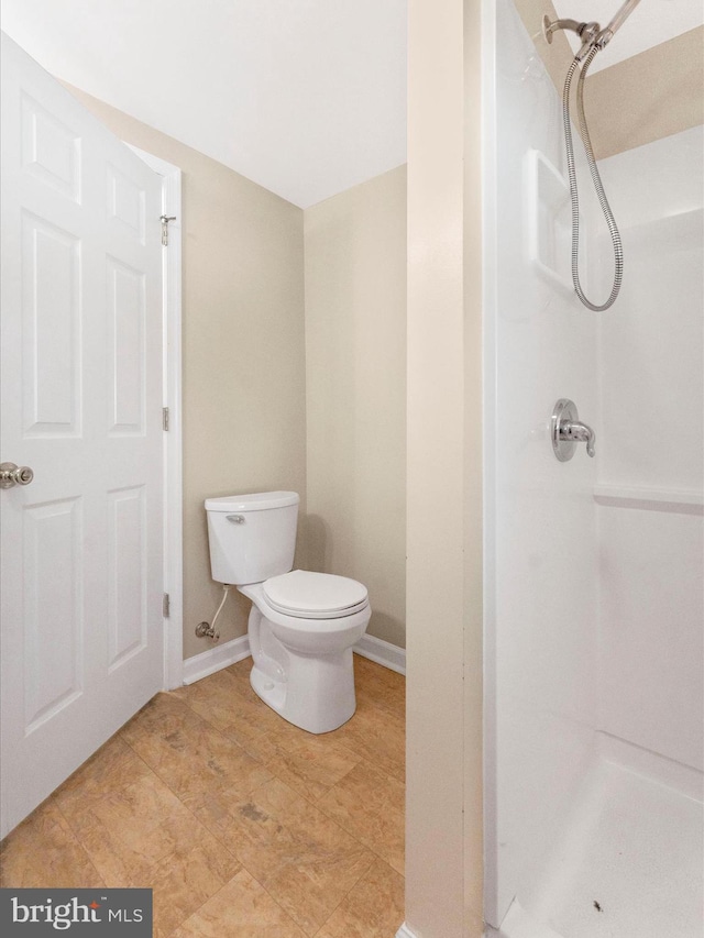 full bath featuring a stall shower, toilet, and baseboards