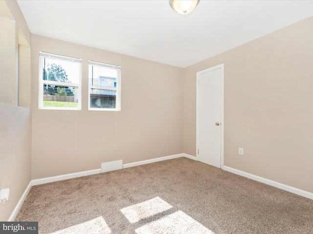 carpeted empty room with visible vents and baseboards