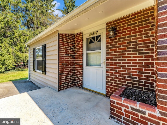 doorway to property featuring a patio area and brick siding