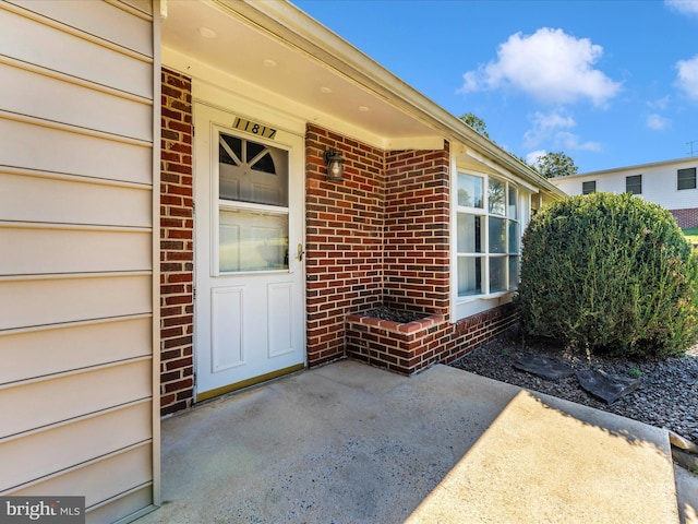 property entrance with a patio area and brick siding