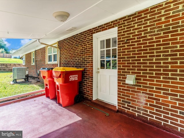 view of exterior entry featuring central air condition unit and a patio