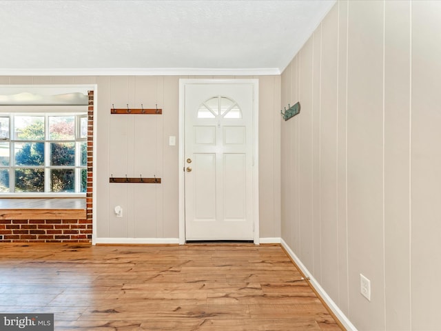 entrance foyer featuring ornamental molding, baseboards, and wood finished floors