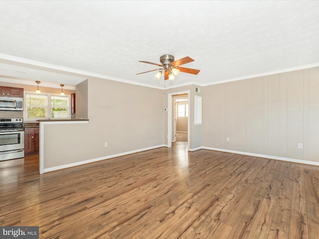 unfurnished living room featuring wood-type flooring, a textured ceiling, ornamental molding, and ceiling fan