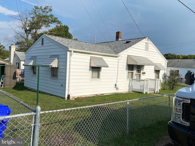 rear view of property featuring a lawn, a fenced backyard, roof with shingles, and a chimney