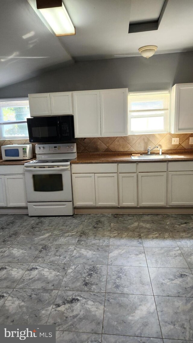 kitchen featuring tile patterned flooring, white appliances, lofted ceiling, and backsplash