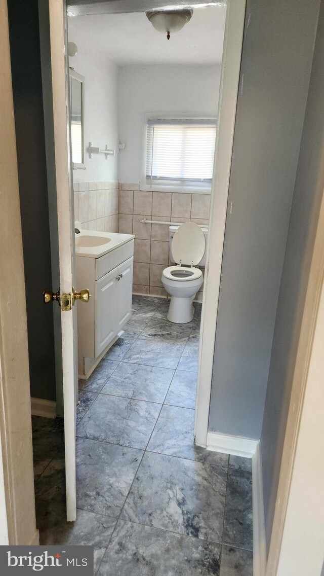 bathroom with tile patterned floors, toilet, vanity, and tile walls