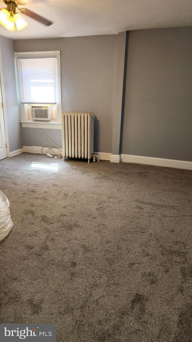 carpeted empty room featuring ceiling fan, cooling unit, and radiator heating unit