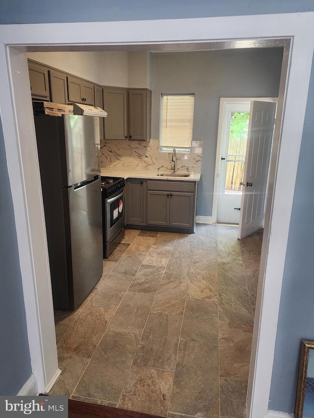 kitchen featuring gas range, light tile patterned floors, sink, and stainless steel refrigerator